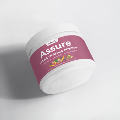 A white container lies on its side, displaying a pink label that reads &quot;Habitly Assure Reds Superfood Powder.&quot; This dietary supplement promises a boost of vitamins, minerals, and antioxidants, with vibrant images of various fruits adorning the label.