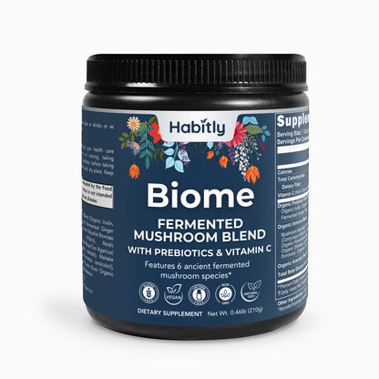 The dark jar labeled &quot;Biome Fermented Mushroom Blend&quot; from Habitly contains an organic mixture that includes prebiotics, probiotics, and vitamin C. The label is adorned with vibrant floral designs and highlights its vegan and dietary attributes. Net weight: 0.46 lb (210g).