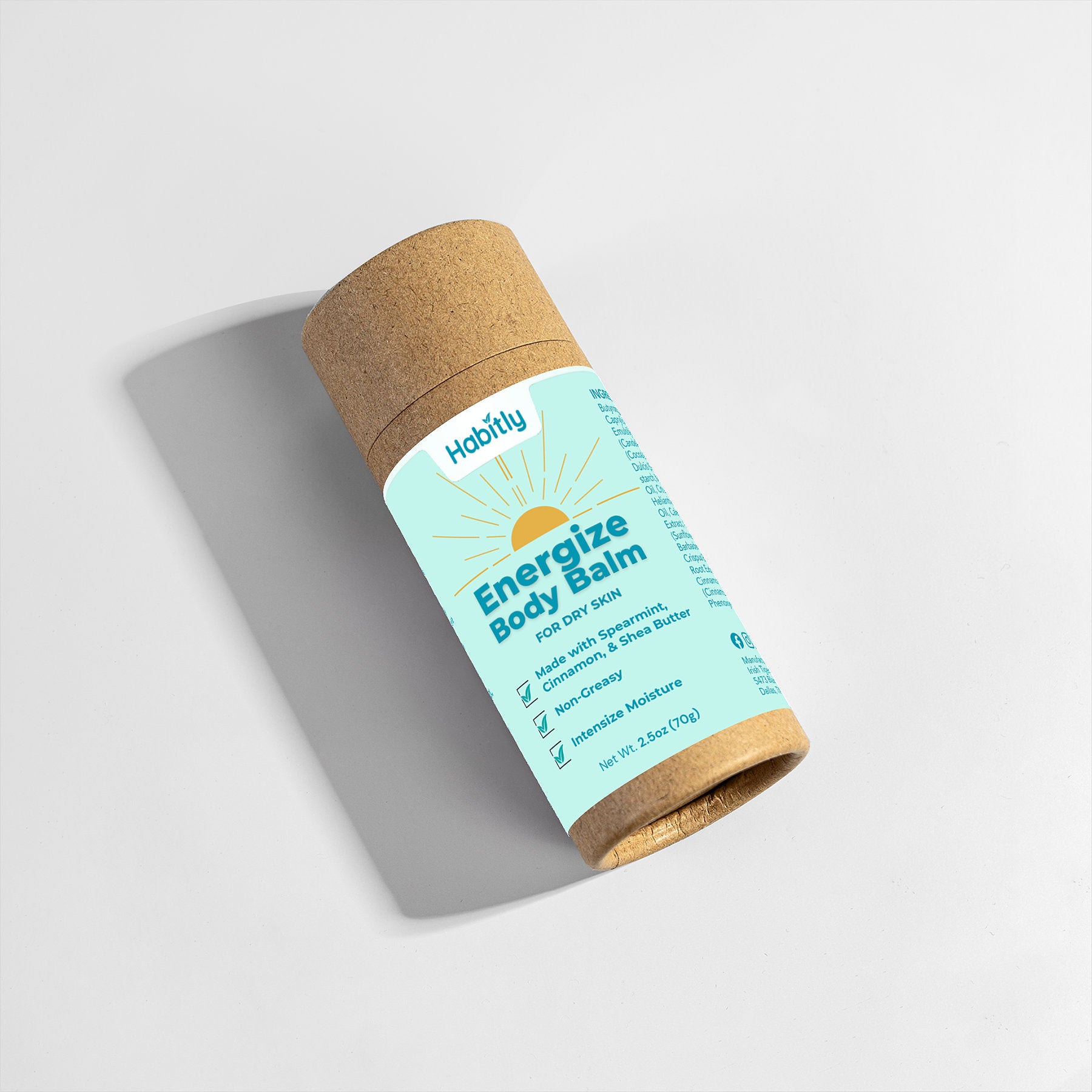 A cardboard tube with a mint green label showcases &quot;Habitly Energize Body Balm.&quot; The product emphasizes deep moisturizing ingredients such as shea butter and aloe, promoting it as incredibly nourishing. Its eco-friendly packaging gently casts a shadow on a light surface.