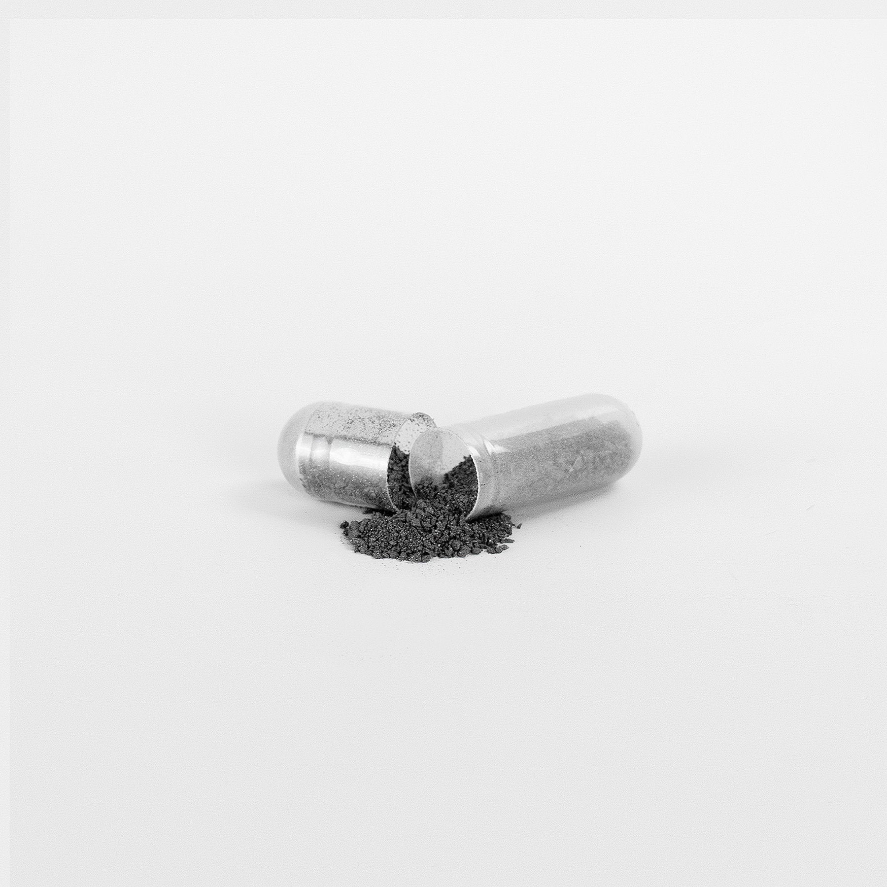 The Move &amp; Groove Natural Gut Wellness Capsules by Habitly are open, revealing a heap of gray powder with fulvic acids spread out on a white surface.