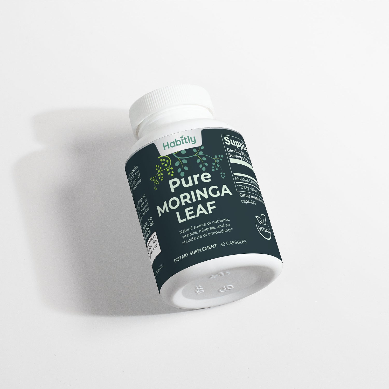 A bottle of &quot;Pure Moringa Leaf Capsules&quot; dietary supplement, known for harnessing the power of Moringa Oleifera and antioxidants, is positioned on its side. The dark label highlights an array of natural vitamins, minerals, and amino acids. With a content of 60 capsules, it prominently showcases the &quot;Habitly&quot; brand name.