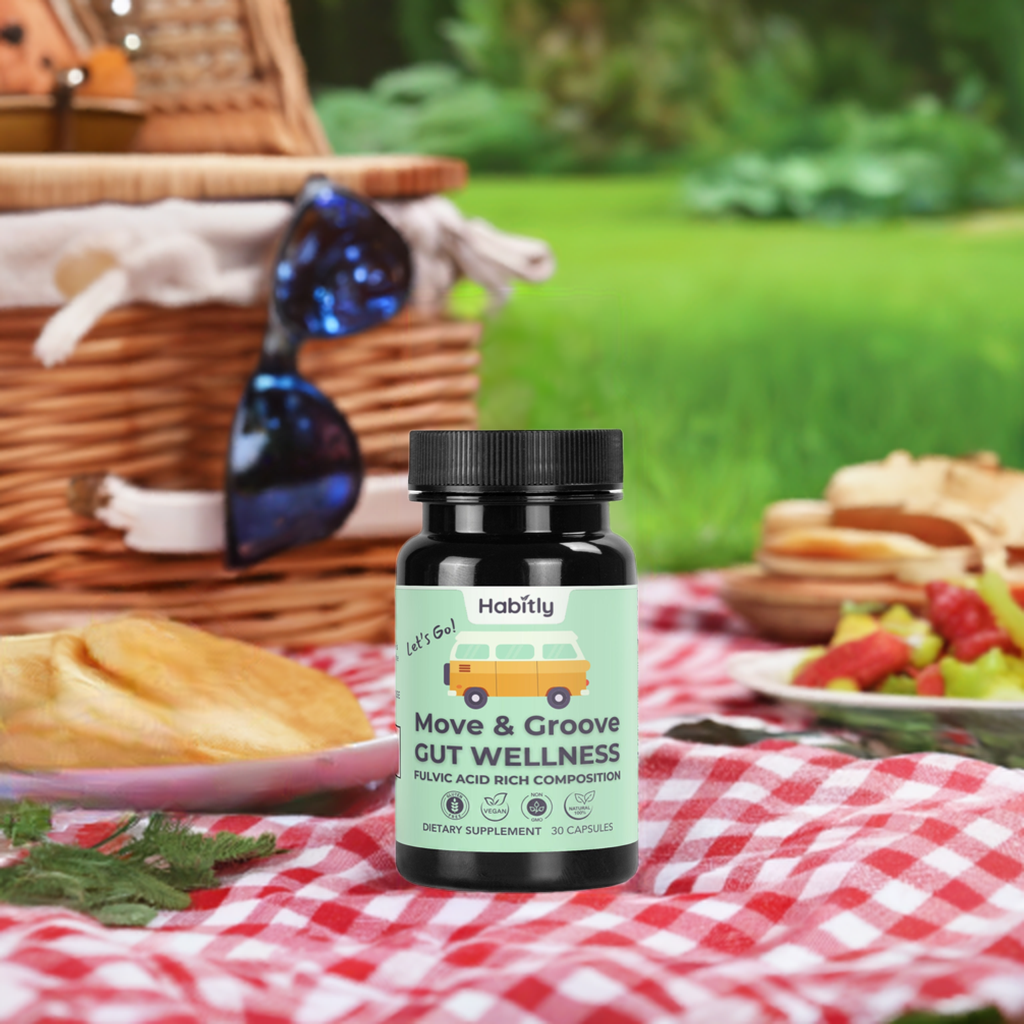 A bottle of &quot;Move &amp; Groove Natural Gut Wellness Capsules&quot; by Habitly featuring Birch Chaga sits on a picnic blanket. The scene is complete with a wicker picnic basket, sunglasses, and plates of assorted food items, all set against the backdrop of a lush grassy area.