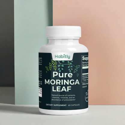 A bottle of Habitly Pure Moringa Leaf Capsules containing 60 capsules is on display. The label emphasizes its nutrient content and antioxidant properties. The background showcases a soft pastel color palette, highlighting the natural essence of this potent botanical formula.